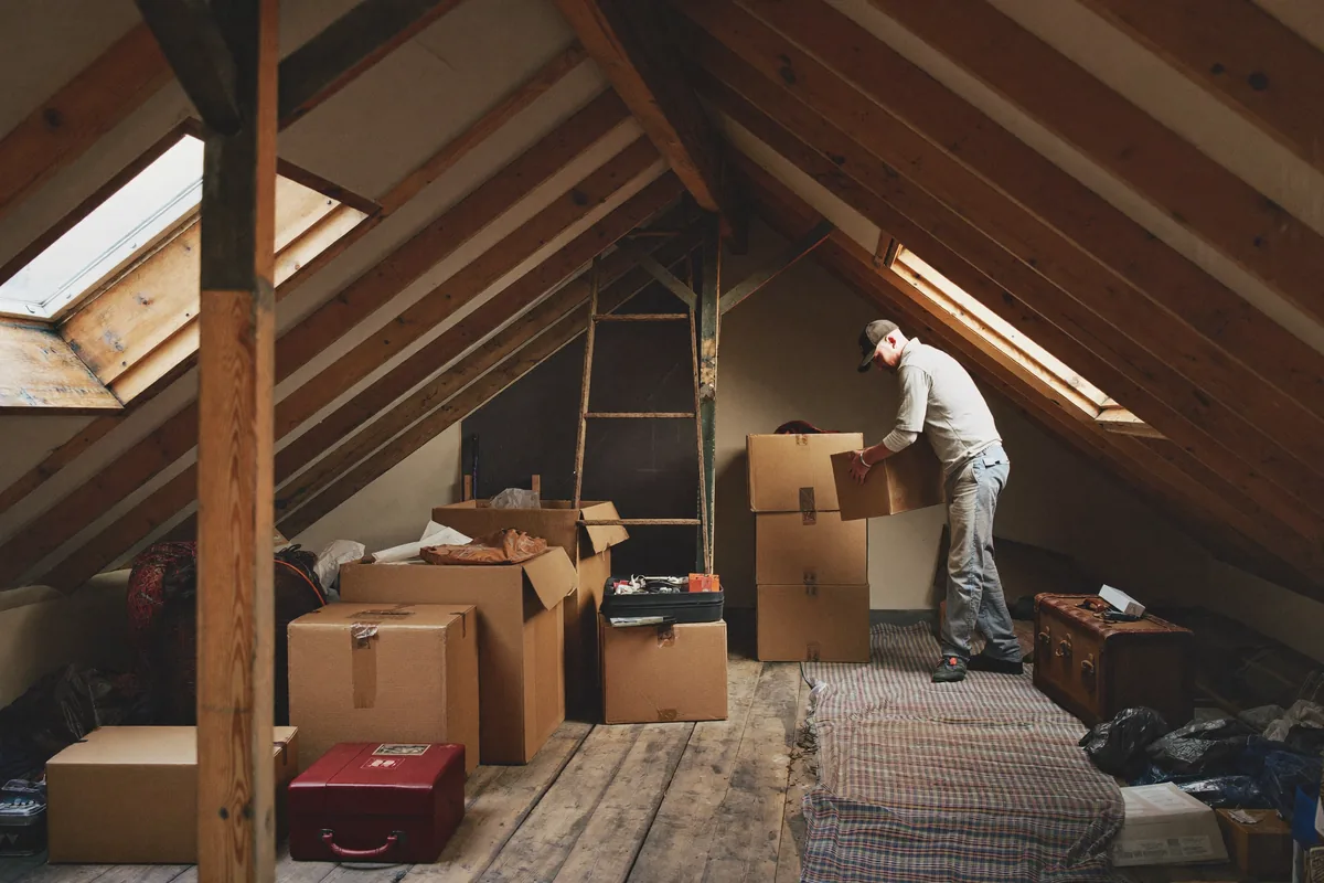 Man and van loft clearance in London — crew bringing boxes and old furniture down from a loft hatch